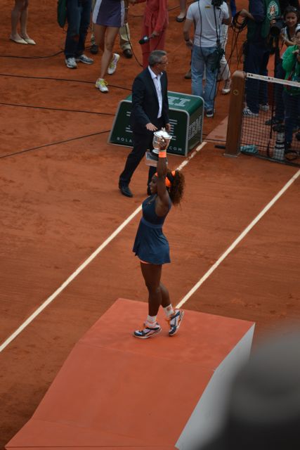 Serena triumphantly holding up her trophy